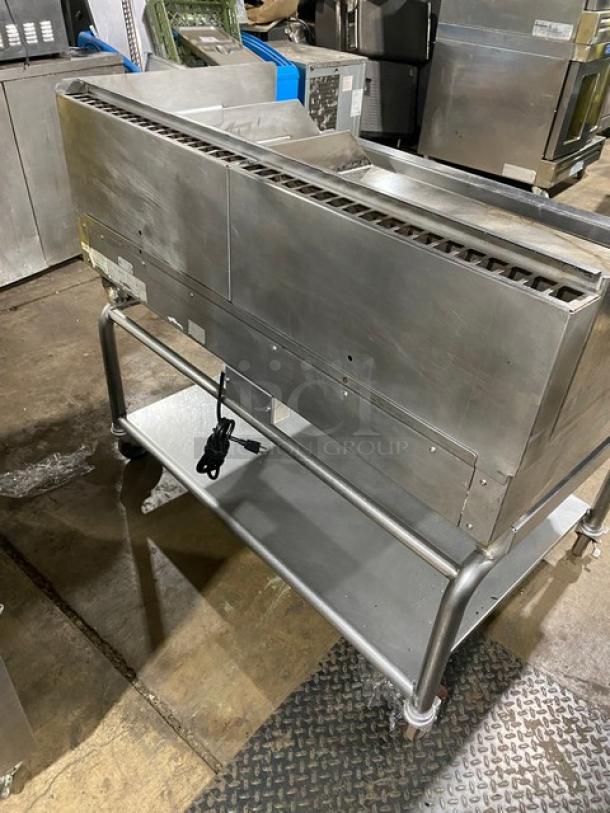 WoodStone stainless steel countertop plancha flat griddle with back and side splash. Natural gas powered, on casters with undershelf cart. SN: GP1B16MAY1704992.