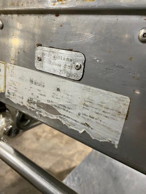 WoodStone stainless steel natural gas plancha griddle with back and side splash, serial number GP1B16MAY1704992, on casters.