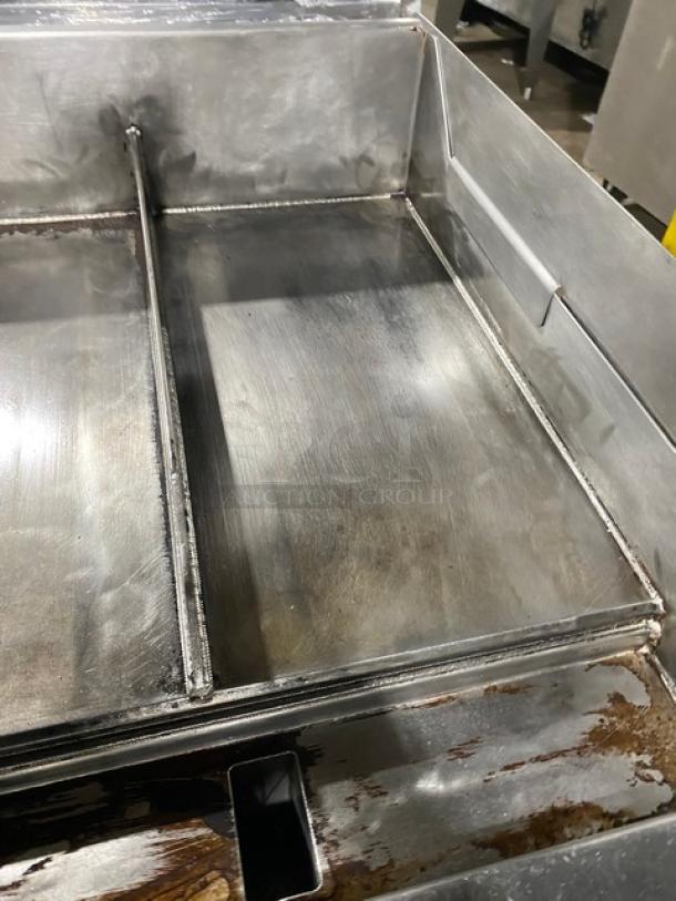 WoodStone stainless steel natural gas-powered plancha flat griddle with back and side splash, on undershelf cart with casters.