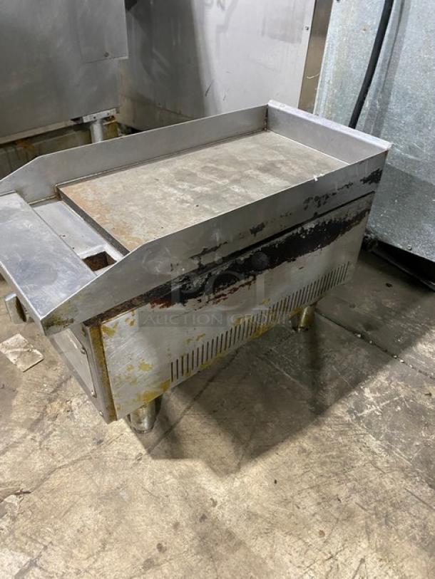 Commercial stainless steel natural gas-powered griddle with back and side splash on legs. Visible wear, durable build.