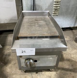 Commercial stainless steel countertop flat griddle with natural gas power, back and side splash, on legs. Visible control knob.