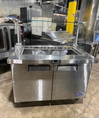 Atosa commercial stainless steel 2-door refrigerated prep table, model MSF8306, with glass sneeze guard and poly-coated rack, on casters.