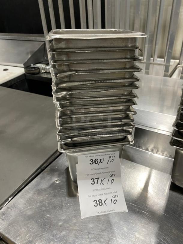 Commercial stainless steel hotel steam table pans stacked; auction tags indicate quantities and auction details.