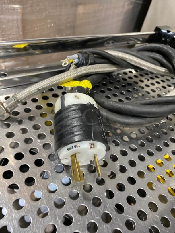 La Marzocco GB/5 2 AV espresso machine plug and cord on perforated metal surface, highlighting power connection details.