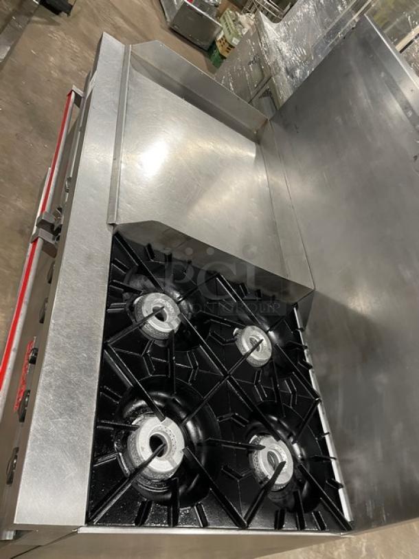 Vulcan commercial stainless steel natural gas split-top flat griddle, 4-burner range, and double oven combo with backsplash and wired oven rack.