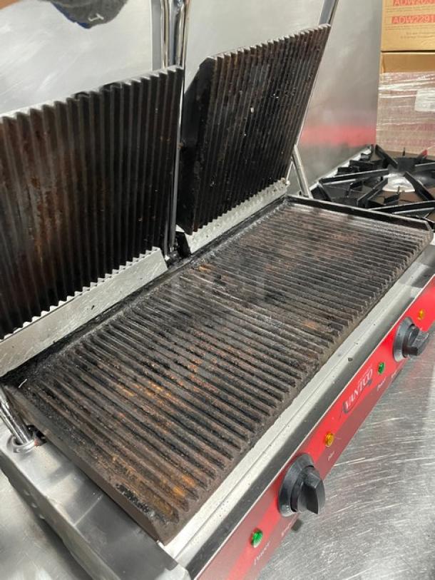 Avantco commercial stainless steel electric panini grill with grooved grates, dual controls, and thermostatic settings.