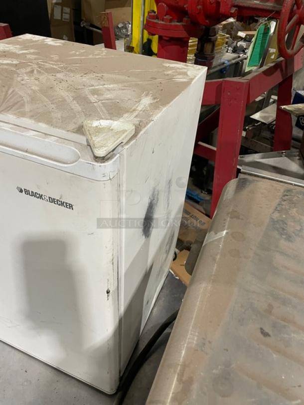 Black & Decker white free-standing refrigerator, Model BCFA27, with upper freezer and poly-coated wire rack. Some surface wear visible.
