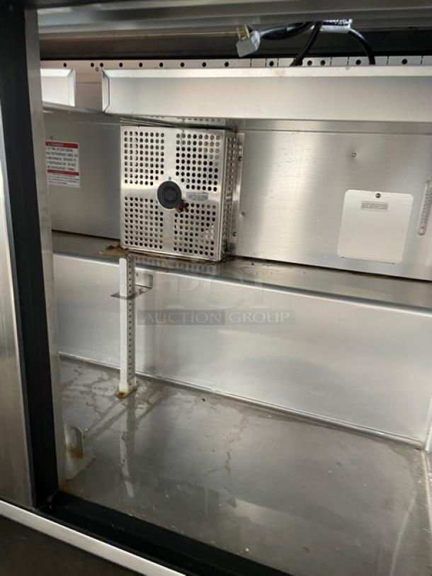True TSSU-48-12-HC stainless steel 2-door refrigerated prep table interior, features adjustable shelf and ventilation panel.