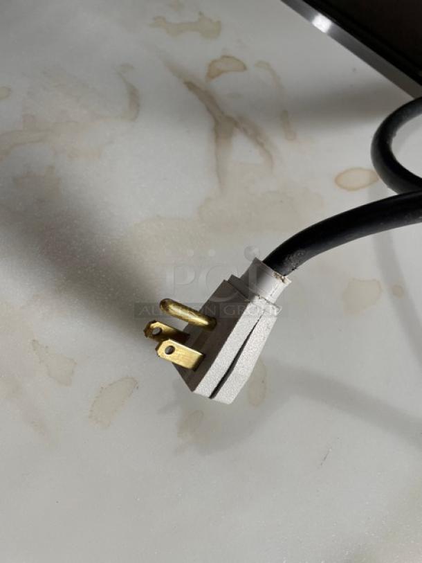 Close-up of an electrical plug for a True TSSU-48-12-HC refrigerated prep table. Standard three-prong design, 115V.