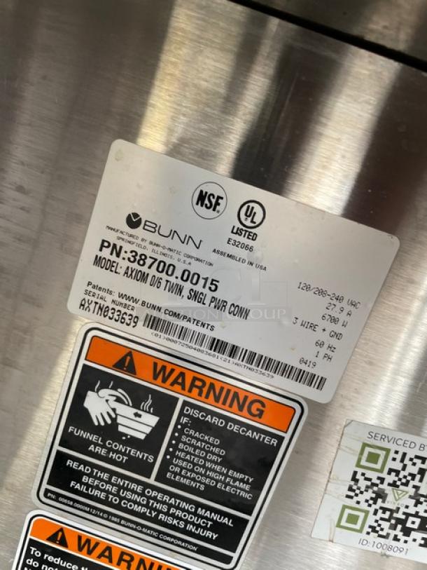 Bunn AXIOM Series twin coffee brewer, stainless steel, with digital controls, hot water dispenser, and 6 warmer plates. Model AXIOM06TWIN, serial number AXTN033639. 120/208-240V, 1 phase. NSF and UL listed labels shown.