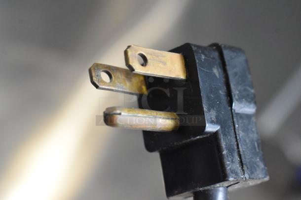 Close-up of a power plug for a True TUC-48F-LP freezer, showing three-pronged configuration and wear.