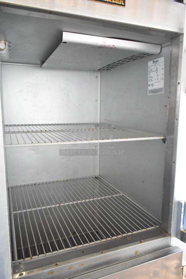 Traulsen G12000 stainless steel commercial freezer with two half-size doors and poly-coated racks. Visible specs on label.