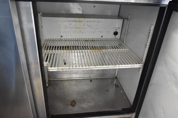 True TSSU-48-12 prep table interior, stainless steel, visible shelving, signs of wear, commercial use, 115V, 1 phase.