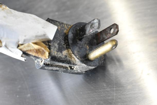 Close-up of a worn electrical plug from a True TPP-67 Pizza Prep Table. The plug shows signs of corrosion and residue.