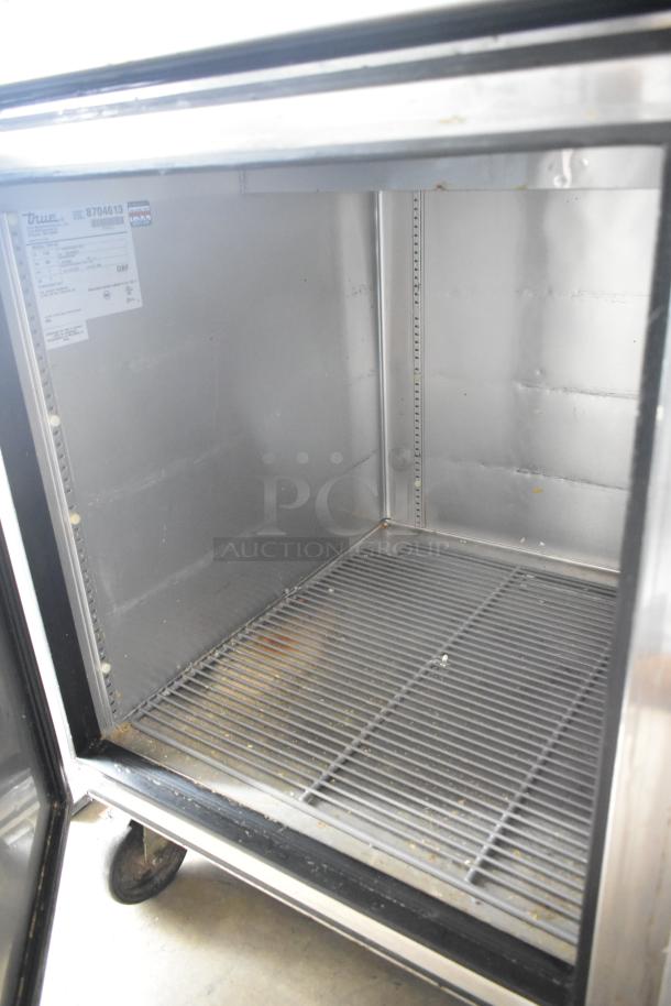 True TPP-67 stainless steel commercial pizza prep table, interior view. Includes commercial casters. Model label visible.