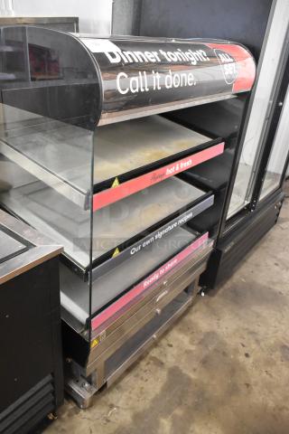 Metal commercial floor-style reach-in warming display case merchandiser with glass front, three shelves, and promotional signs.