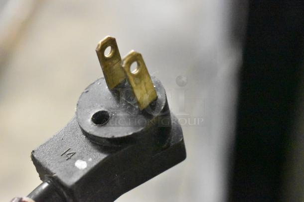 Close-up view of a black power plug with two brass prongs, part of the Beverage Air UCR34Y cooler.