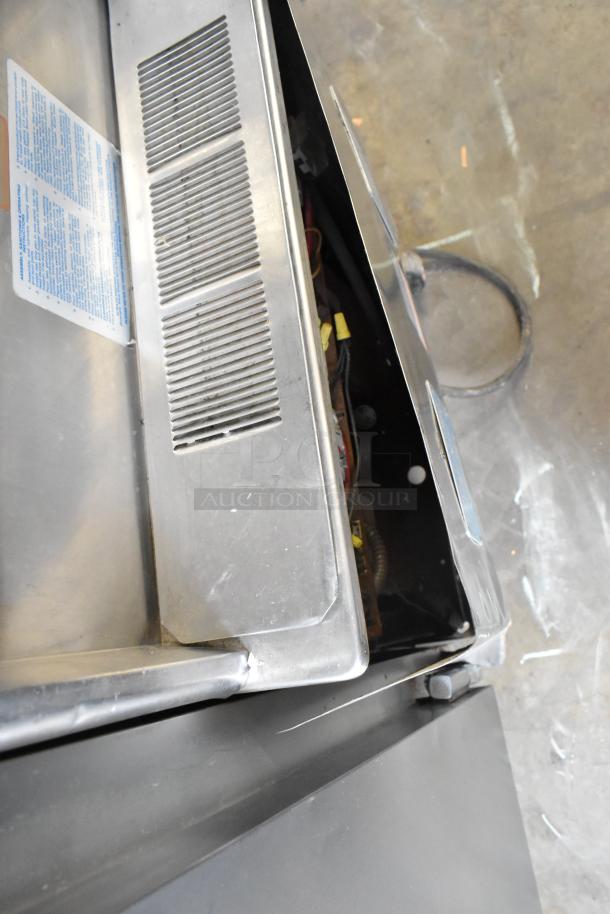 Taylor 754-27 stainless steel soft serve machine, commercial casters, open panel view. Model and voltage info not shown.