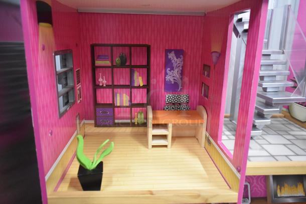 Doll playhouse interior with pink walls, wooden floor, bookshelf, desk, and stairs. Modern design, vibrant decor.