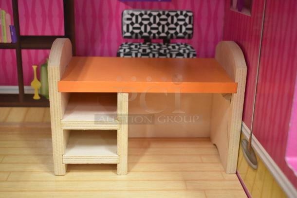 Doll playhouse interior featuring an orange desk with shelves, detailed wallpaper, and a monochrome patterned chair.
