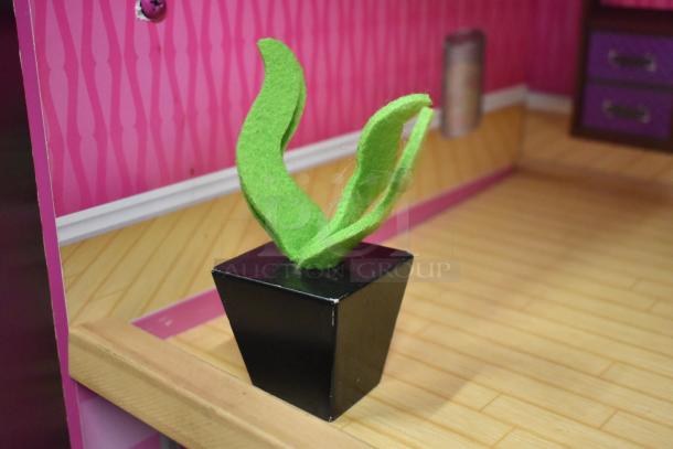 Doll playhouse interior with pink striped wallpaper, wooden floor, and a small black planter with green felt leaves.