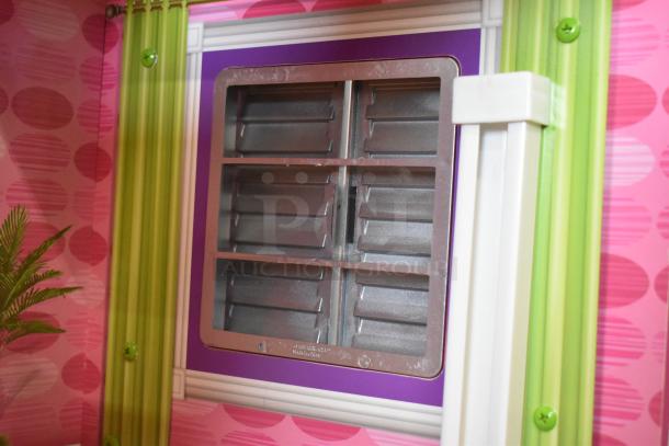 Doll playhouse with colorful design, featuring a detailed window with shutters. Pink and green decor, in good condition.