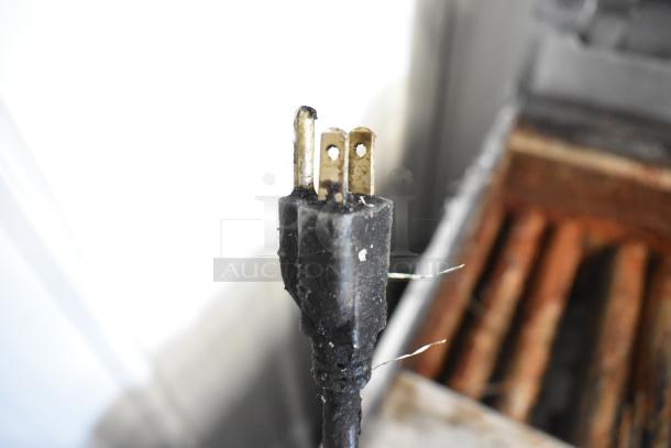 Close-up of a damaged three-prong electrical plug with frayed wires, indicating possible repair needs.