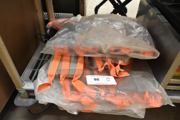 Lot of orange straps in plastic bags, labeled "98 QTY 1 lot," minimal visible wear, stored on a metal cart.