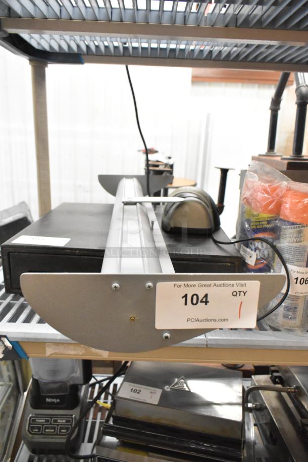 Roll up sign in metal casing, labeled "104 QTY" for auction, in good condition on warehouse shelf.
