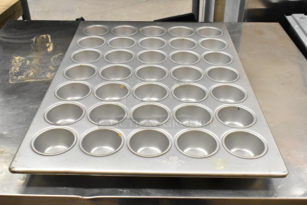 5 various metal items including 35-cup muffin baking pan, round baking pan, and bowl. Used condition, minor wear visible.