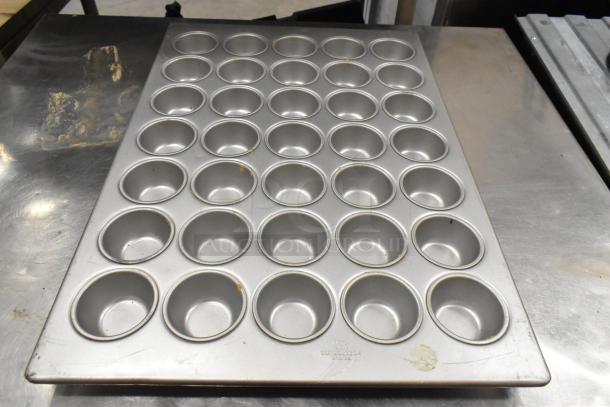 5 Various metal items, including a 35-cup muffin pan, round baking pan, and bowl. Good condition, marks visible.