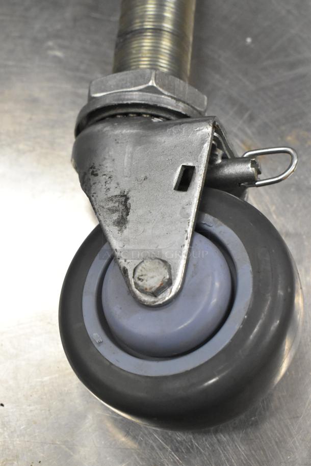 Commercial caster wheel with metal frame and locking mechanism, in used condition, suitable for heavy-duty applications.