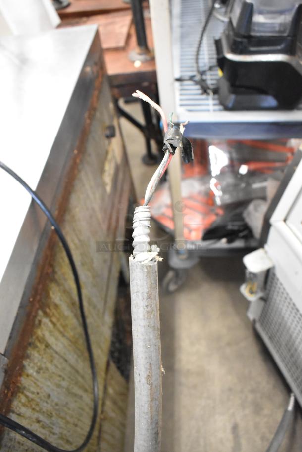 Electrical cable in need of repair, frayed and exposed, potentially part of Turbo Air TB-5R refrigerated bakery case.