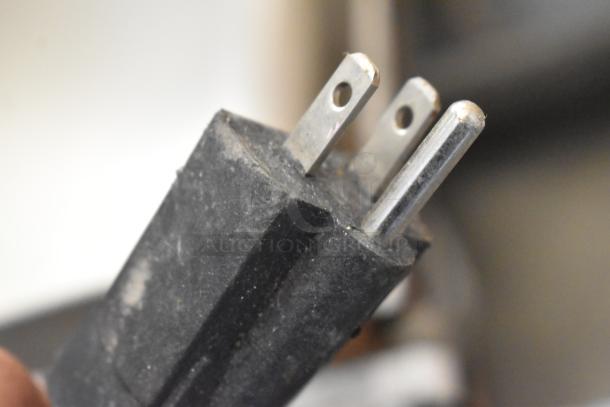 Close-up of a three-prong plug for the Gayke NP-229 waffle maker, highlighting the 110-volt power connection.