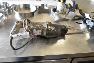 Old jigsaw, 115 volts, 1 phase, with visible wear. Auction tag marked “114” attached.