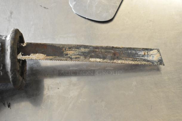 Rusty jigsaw blade, 115 volts, 1 phase, showing signs of wear on a stainless steel surface.