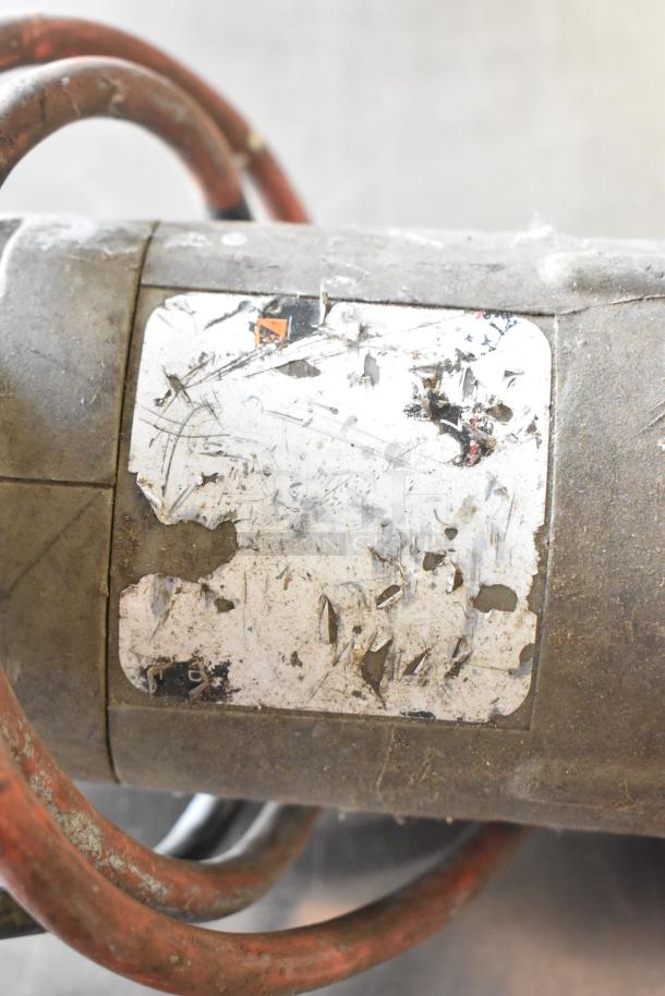 A jigsaw with visible wear, featuring a scratched metal body and faded label. Powered at 115 volts, 1 phase. 