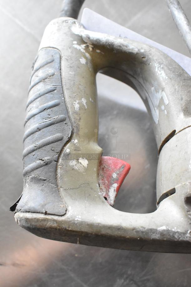 Worn jigsaw handle with red trigger, 115 volts, 1 phase. Visible wear and scuffs indicate usage.