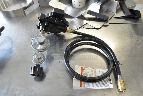 Black gas hose with metal regulators and connectors, includes tag with safety instructions. Good condition, used for propane tanks.