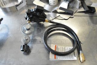Black gas hose with metal regulators and connectors, includes tag with safety instructions. Good condition, used for propane tanks.