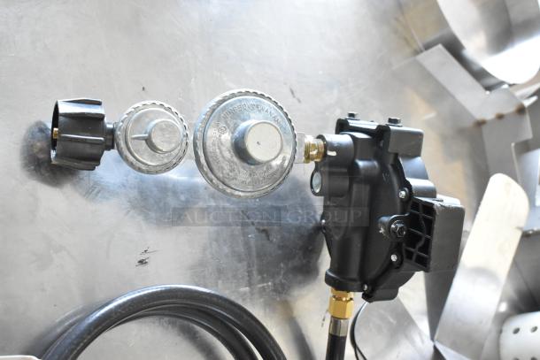 Gas hose with metal regulator and black plastic valve, connecting to brass fitting. Appears in good condition.