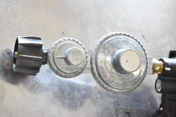 Gas hose with attached metal regulators, marked "Ningbo Wanxin," durable condition, suitable for gas appliances.