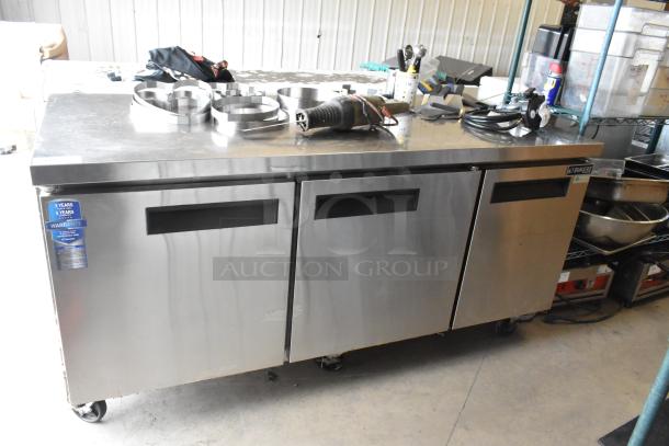 Dukers DUC72R stainless steel 3-door undercounter cooler with commercial casters, 115V, warranty label visible.