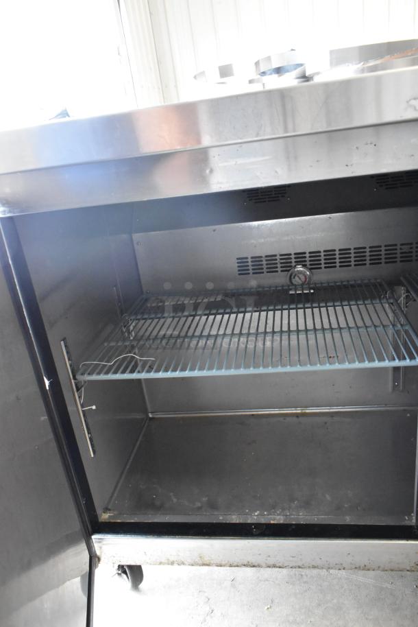 Dukers DUC72R stainless steel 3-door undercounter cooler on casters, interior view, showing wire shelf and thermometer.