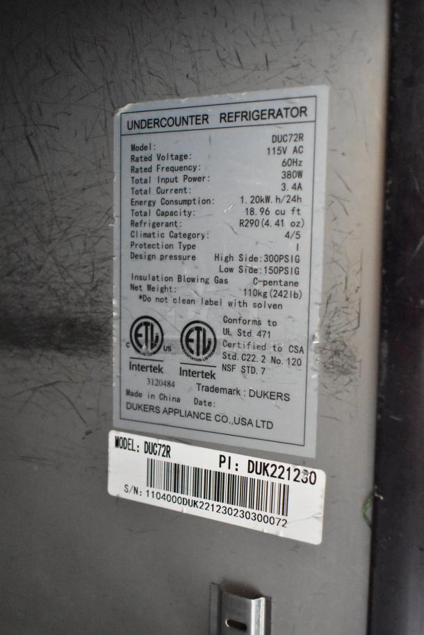 Dukers DUC72R commercial 3-door undercounter cooler on casters, stainless steel, 115V, model tag visible with specs.