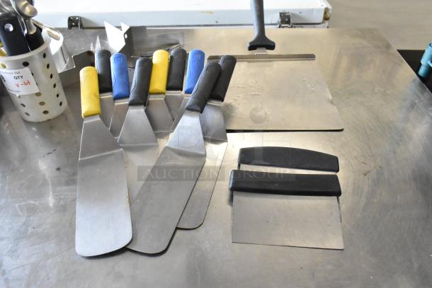 Lot of kitchen tools: spatulas with colorful handles, pastry paddle, cake collars. Good condition. Auction label visible.