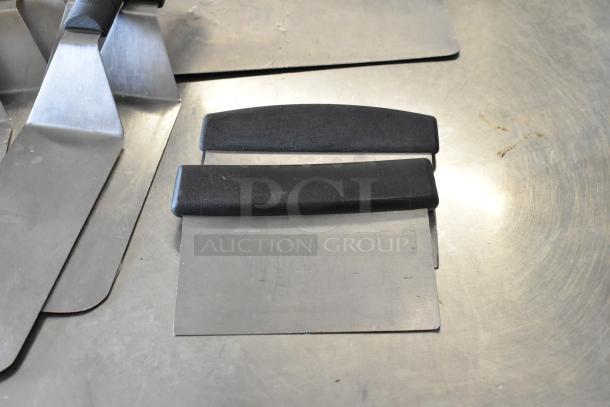 Assortment of cooking tools including spatulas and cake collars on a metal surface, fair condition.