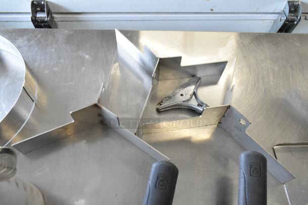 Lot of various kitchen items including metal spatulas, paddle, and cake collars, on a metal surface.