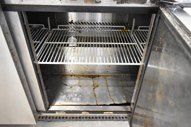 2017 Bison BUR-72 stainless steel 3-door undercounter cooler, showing interior shelves. Visible wear and stains on surfaces.