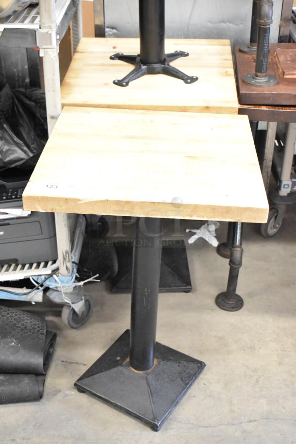Eight tables with sturdy wooden tabletops and black metal bases. Slight wear. Number "123" marked on one.